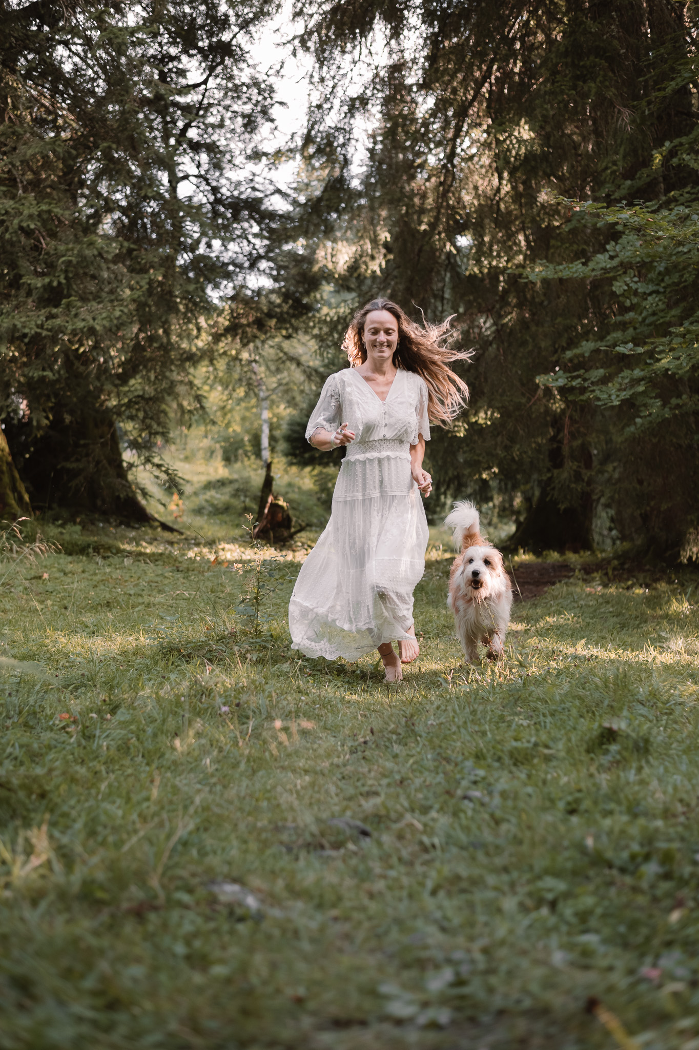 Portrait bohème en forêt, modèle posé avec un chien, lumière douce et naturelle.